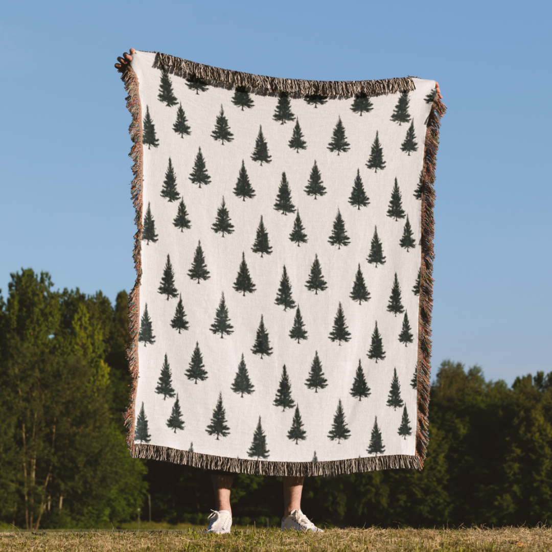 a person holding a blanket with trees on it