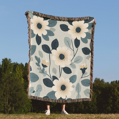 a person standing in a field holding a blanket with flowers on it